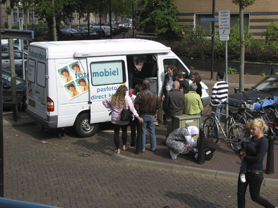 908008 Afbeelding van wachtende mensen voor de fotomobiel ('pasfoto's direct klaar'), voor het kantoor van de Dienst ...